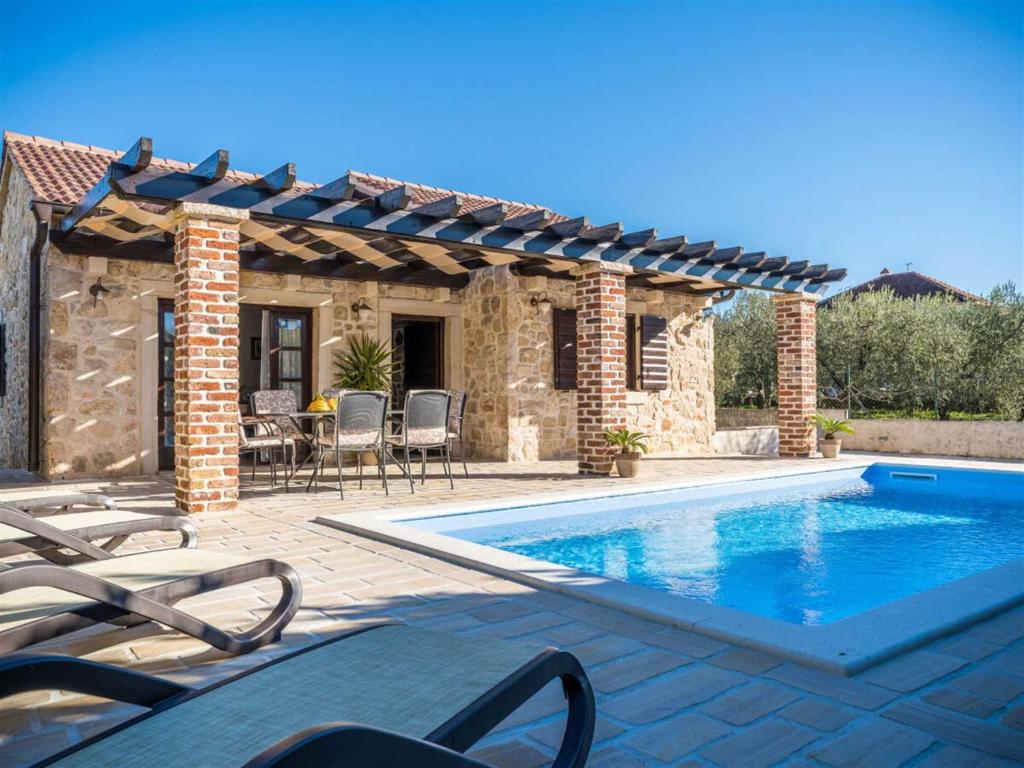 eine Terrasse mit Pool und ein Haus in der Unterkunft Stone Villa Petit Rustica with pool in Sukošan