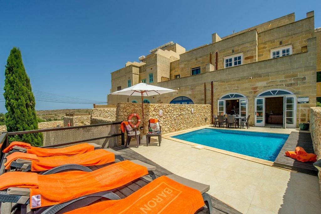 Villa con piscina frente a un edificio en Hanini Holiday Home en Qala