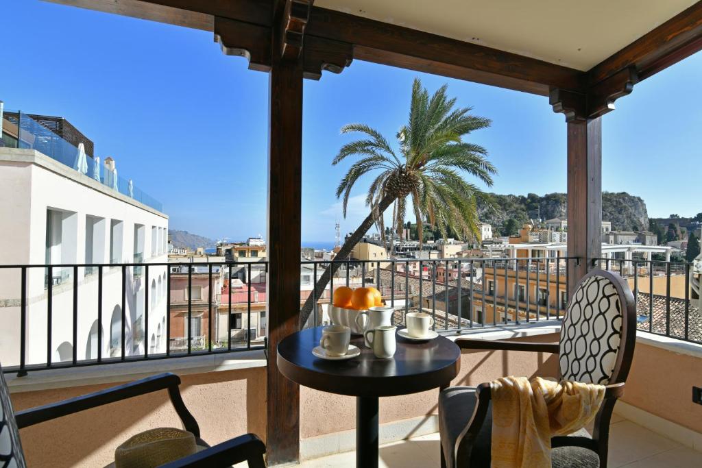 une table et des chaises sur un balcon avec un palmier dans l'établissement Hotel Le Chevalier, à Taormine