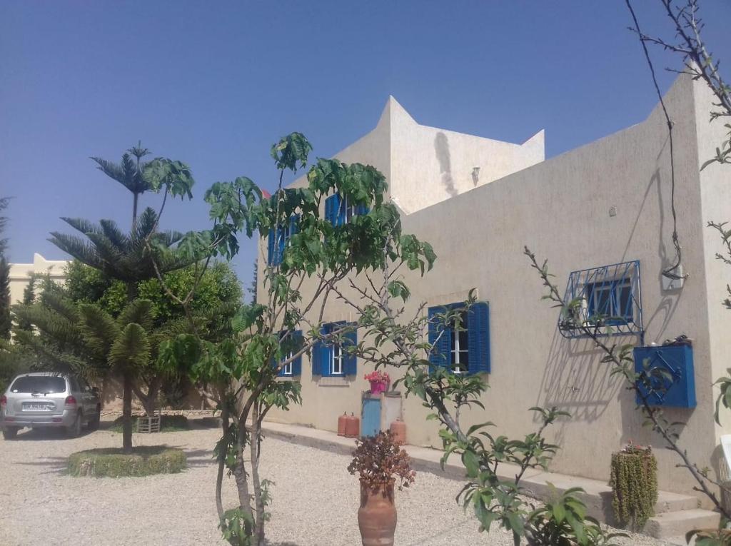 a building with blue windows and trees in front of it at maison calme et reposante in Essaouira