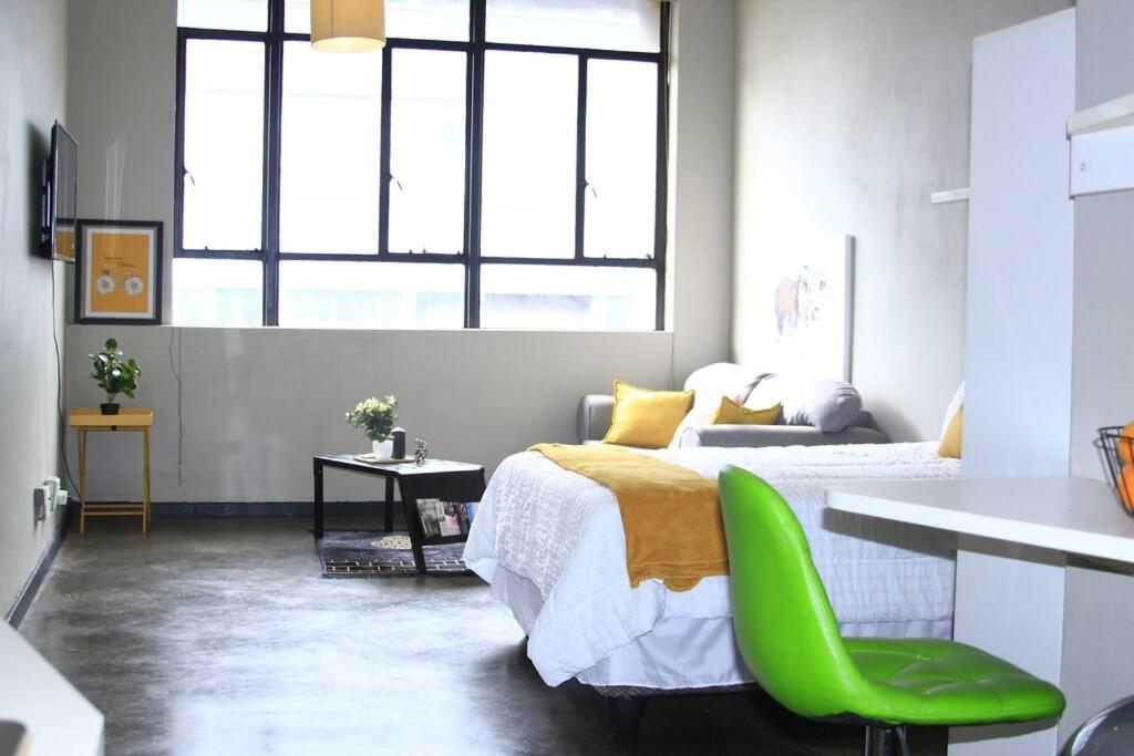 1 dormitorio con 1 cama y 1 silla verde en Air: Fox on Maboneng, en Johannesburgo