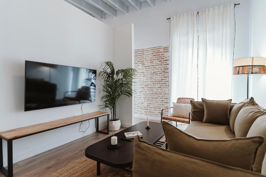 salon z kanapą i telewizorem na ścianie w obiekcie One&Lux Puñonrostro Bright Minimalist Central Home w Sewilli