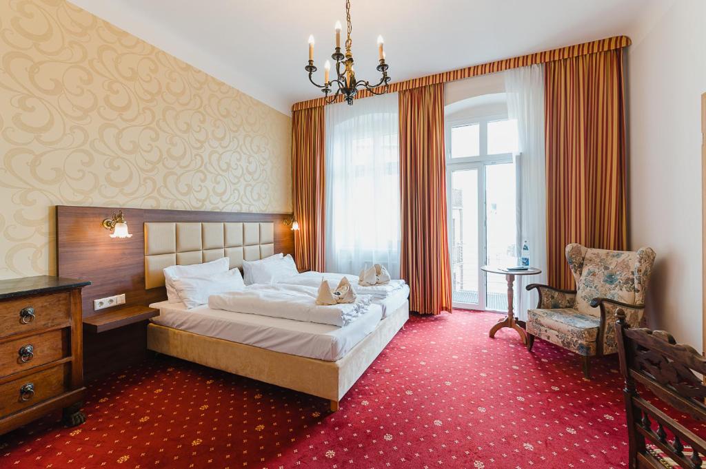 a bedroom with a large bed and a chair at Hotel Alt Görlitz in Görlitz