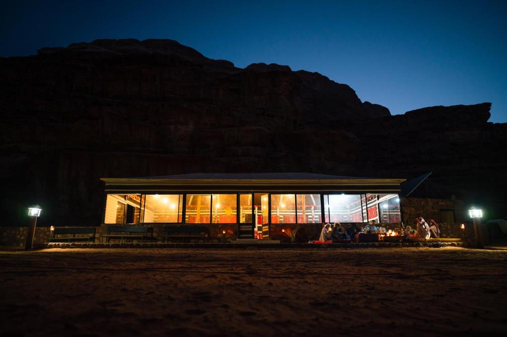 a building at night with a mountain in the background at Milky Way Bedouin Camp in Wadi Rum