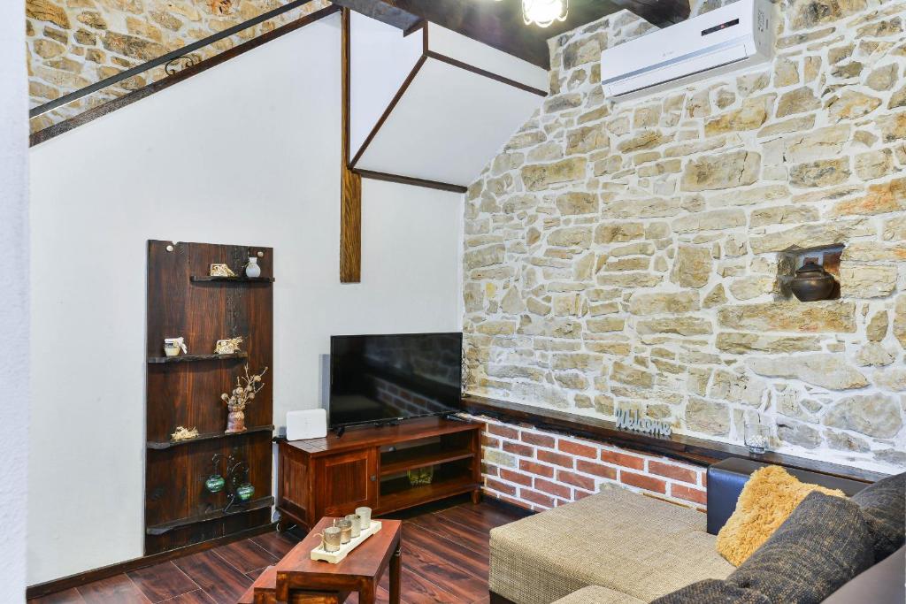 salon z kamienną ścianą i kanapą w obiekcie Stone Villa Mia with pool w mieście Debeljak