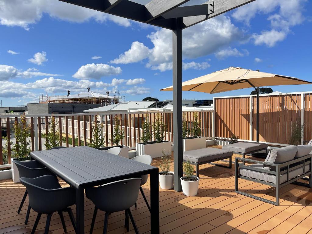 eine Terrasse mit einem Tisch, Stühlen und einem Sonnenschirm in der Unterkunft The Bright Home Torquay in Torquay