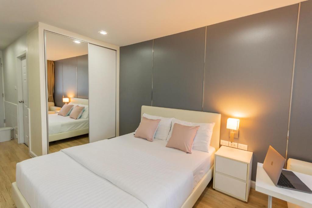 1 dormitorio con cama blanca y espejo en United Residence Ekamai Bangkok, en Bangkok