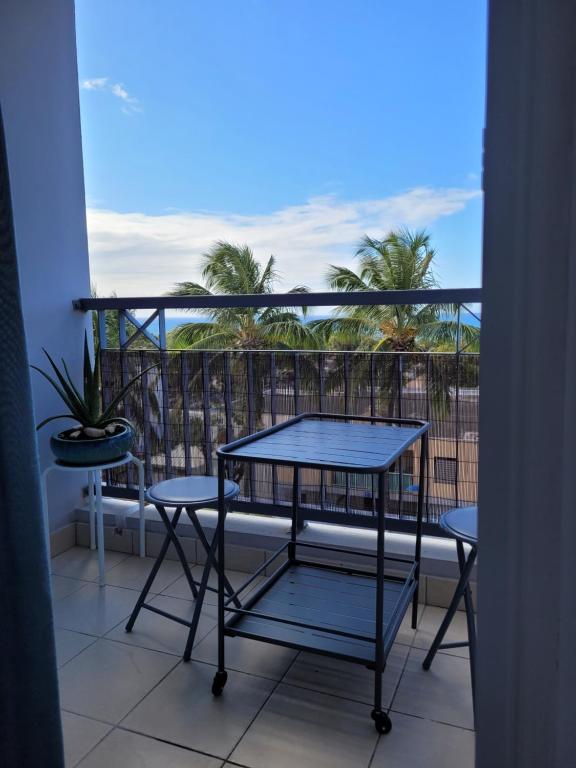 een balkon met een tafel en stoelen en palmbomen bij Escale 86 in Sainte-Marie