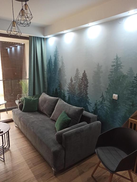 ein Wohnzimmer mit einem Sofa und einer Wand mit einem Waldbild in der Unterkunft Borovi30 in Divčibare