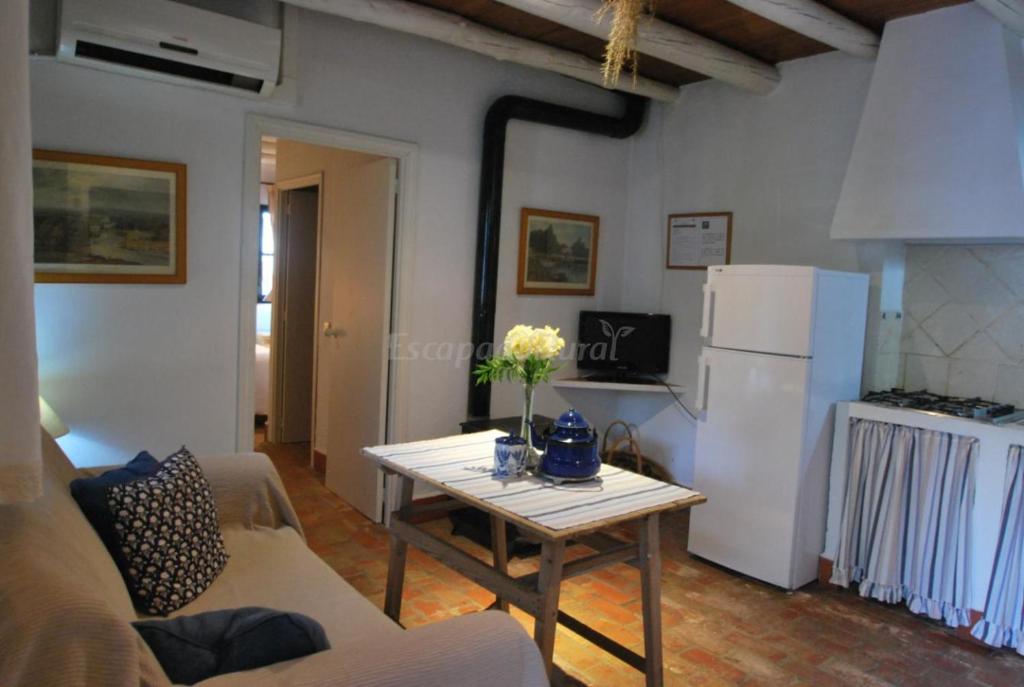 een woonkamer met een tafel en een witte koelkast bij Finca La Vicacaria LIMONERO in Zufre