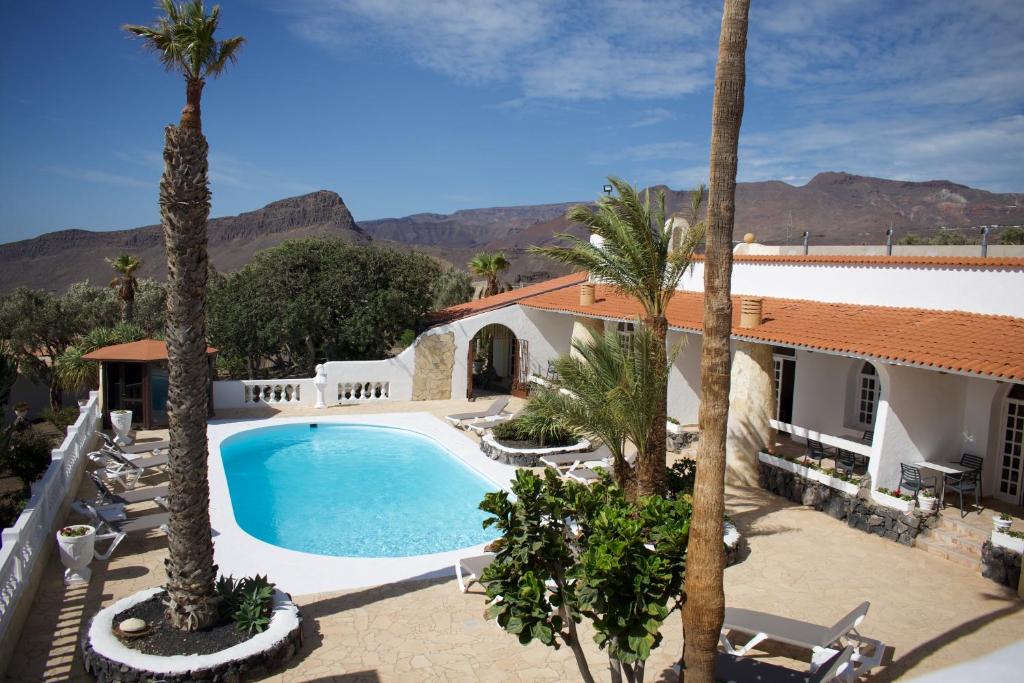 a villa with a swimming pool and palm trees at Wohnung Aulaga in Agüimes