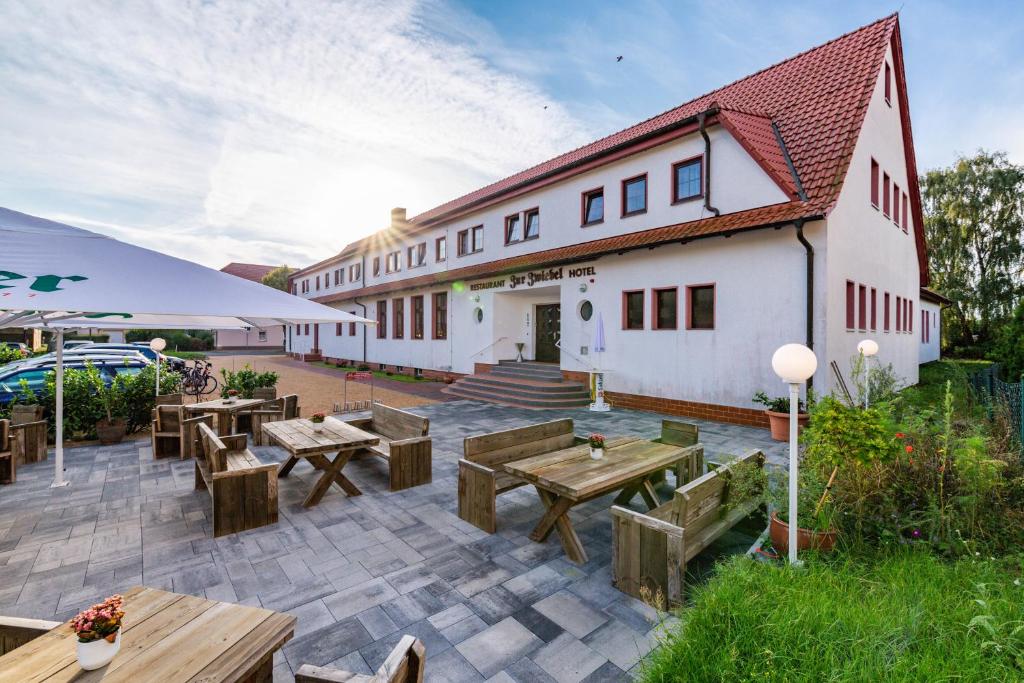 patio z drewnianymi stołami i budynkiem w obiekcie Hotel & Restaurant Zur Zwiebel w mieście Peenemünde