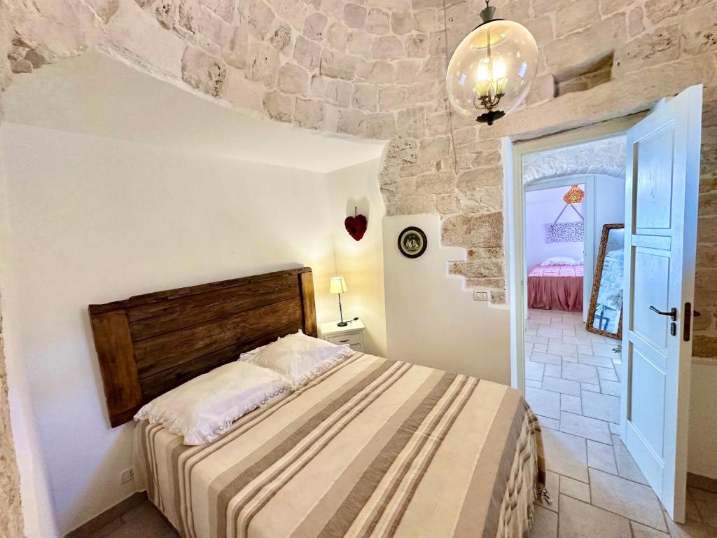 une chambre avec un lit et un mur en pierre dans l'établissement Trullo il Carrubo, à Alberobello