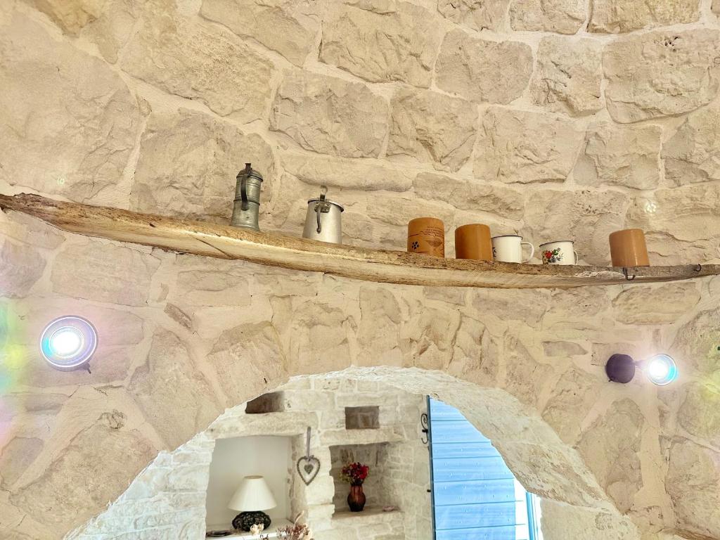 un mur en pierre avec une étagère dans une pièce dans l'établissement Trullo il Carrubo, à Alberobello