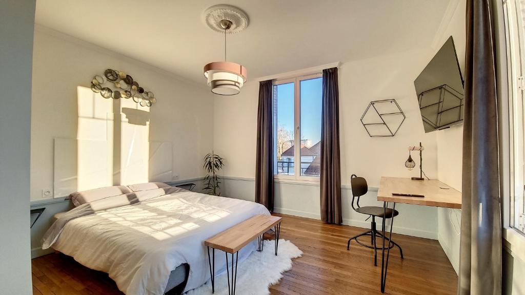 Schlafzimmer mit einem Bett, einem Schreibtisch und einem Fenster in der Unterkunft Appart spacieux et lumineux à 5 min de la gare in Troyes