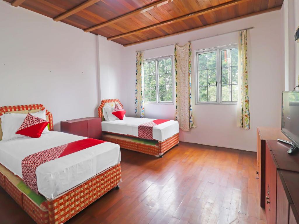 a bedroom with two beds and a flat screen tv at OYO 91807 Kemalasari Guesthouse in Jambi