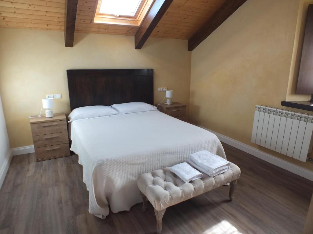 a bedroom with a large white bed and a bench at Apartamentos Puerta del Castro in Coaña