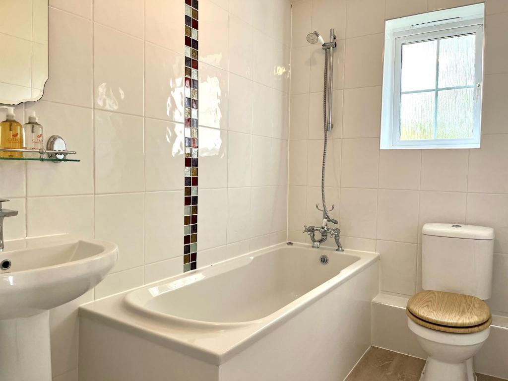 a bathroom with a tub and a toilet and a sink at Comfortable 3 bedroomed house in Bicester in Bicester