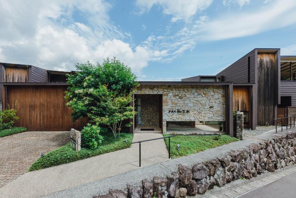 an external view of a house with a stone wall at Terrace Midoubaru in Beppu