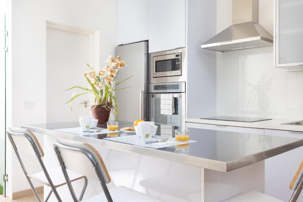 eine weiße Küche mit einer Theke und Stühlen in der Unterkunft Home2Book La Casita del Mercado in Santa Cruz de Tenerife
