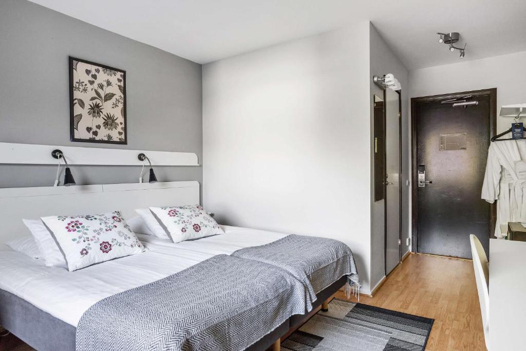 una camera con un letto bianco con due cuscini di Best Western Hotell SoderH a Söderhamn
