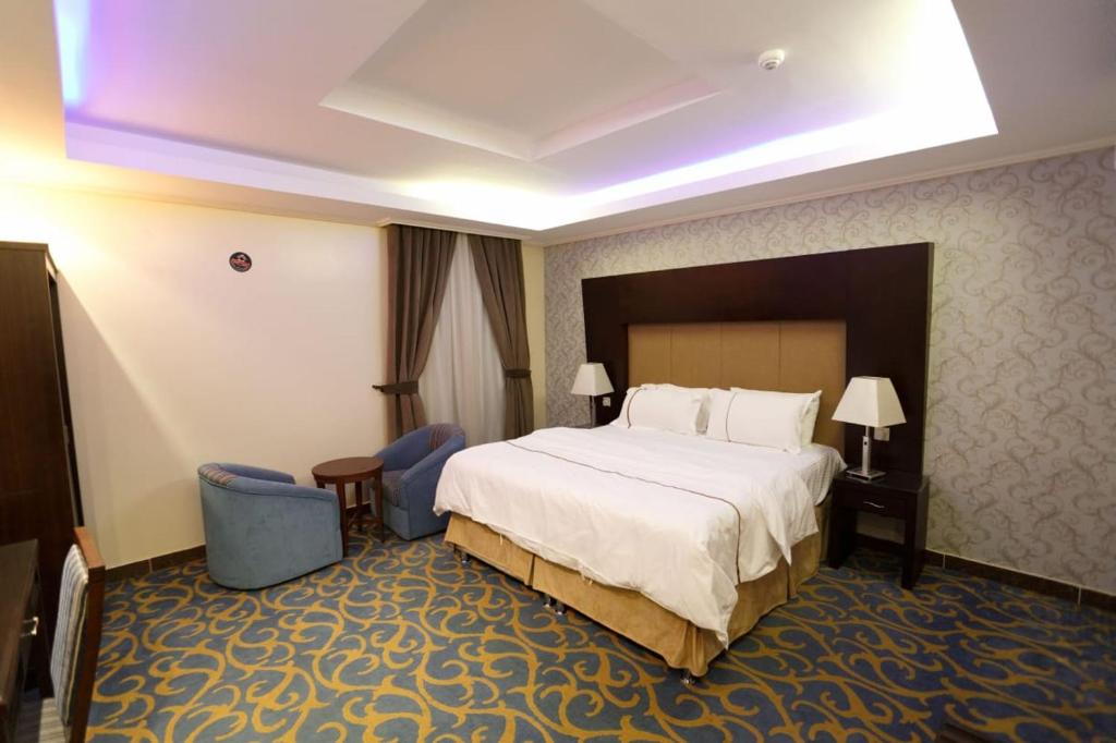 a hotel room with a large bed and two chairs at قصر اليمامة للشقق المخدومة Al Yamama Palace Serviced Apartments in Yanbu