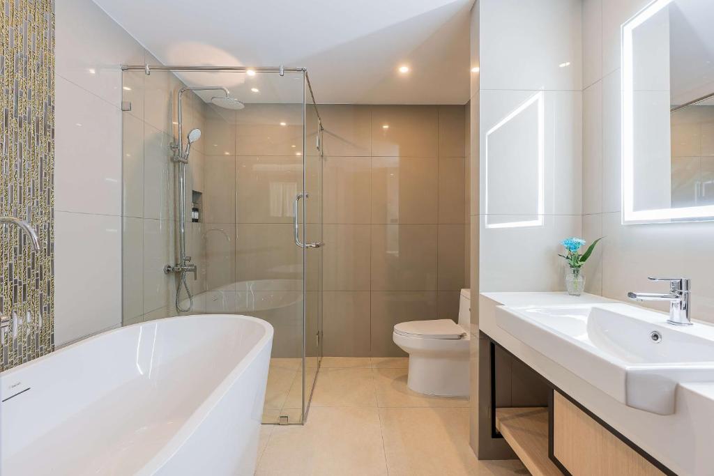 A tiled bathroom with a freestanding bathtub, enclosed shower and wide vanity.