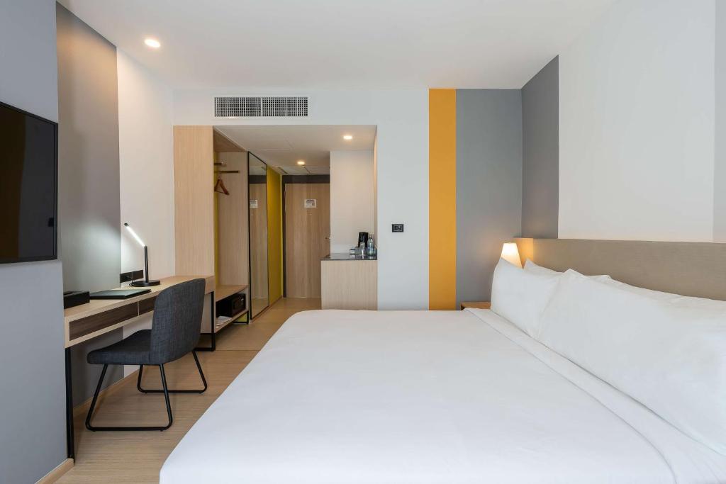 A modern king room pairs a large bed with a compact workstation and kitchenette cabinet.
