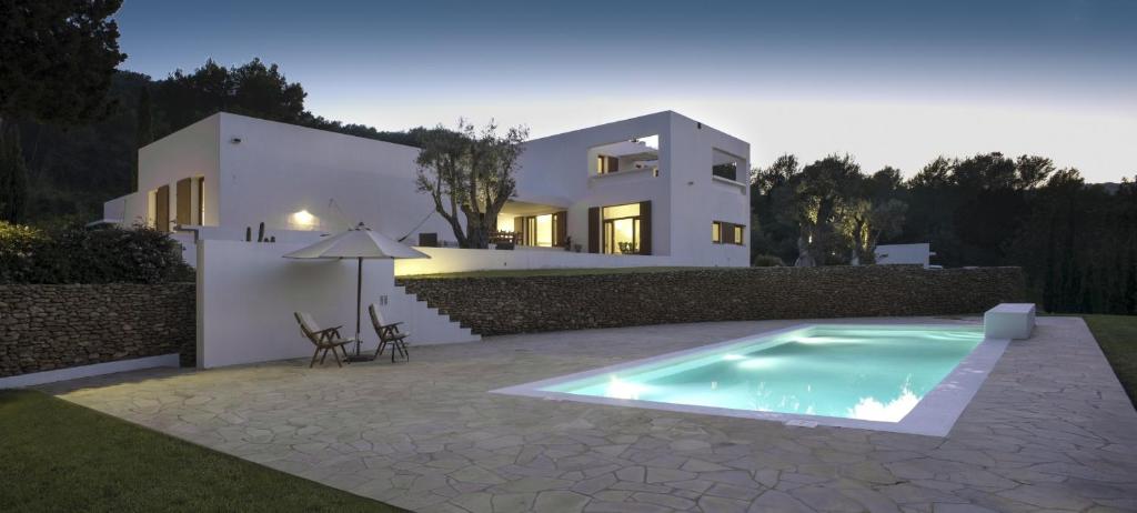 a villa with a swimming pool in front of a house at White House Ibiza Modernist Design Can Perez Sea views Es Figueral in Santa Eularia des Riu