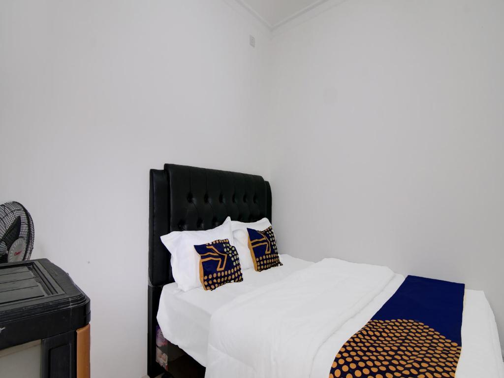 Una cama con cabecero negro y almohadas. en SPOT ON 91828 Homestay Dinda Syariah, en Parit