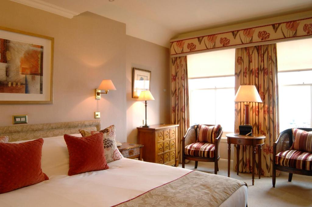 a hotel room with a bed and two chairs at Wentworth Hotel in Aldeburgh