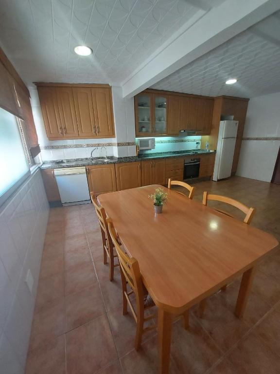 eine große Küche mit einem Holztisch und Stühlen in der Unterkunft Gran apartamento con la playa a 2 kilómetros para familias in San Juan de Alicante