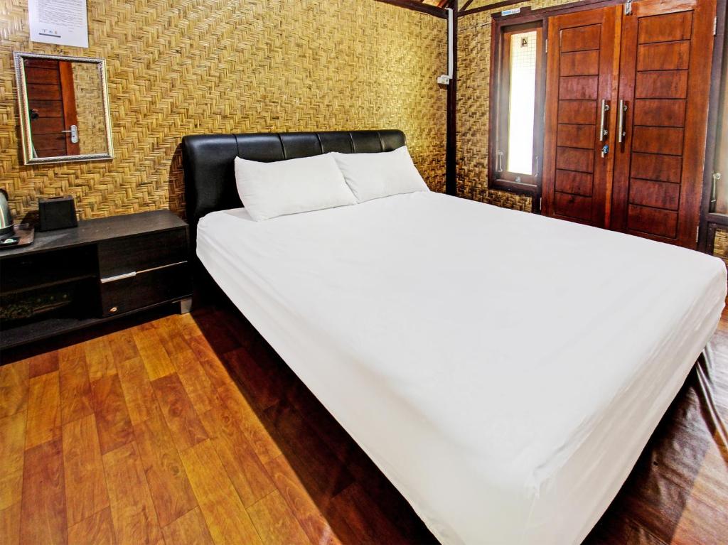 een groot wit bed in een kamer met een bureau bij OYO 91830 Hotel Gemilang 2 in Lombok
