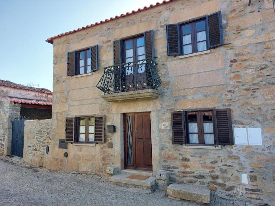 un antico edificio in pietra con balcone e porta di Casa Férias Retiro do Rodeiras a Figueira de Castelo Rodrigo