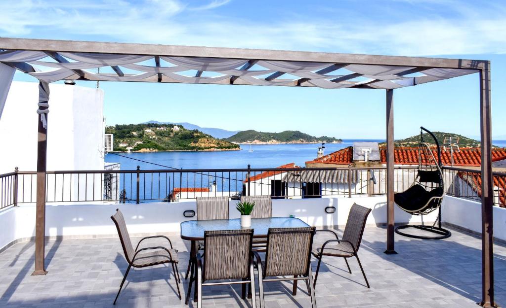 a patio with a table and chairs and a view of the ocean at La Maison Plakes Rooftop Apt in Skiathos