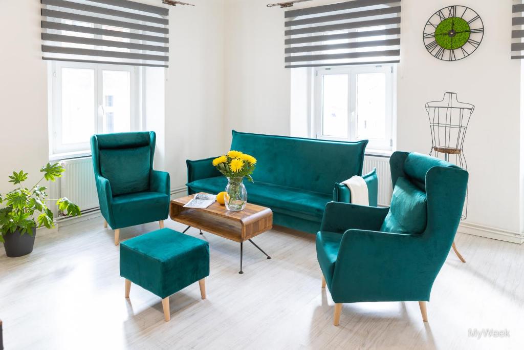 a living room with two green chairs and a table at Apartament z historią, Klahra MyWeek in Lądek-Zdrój