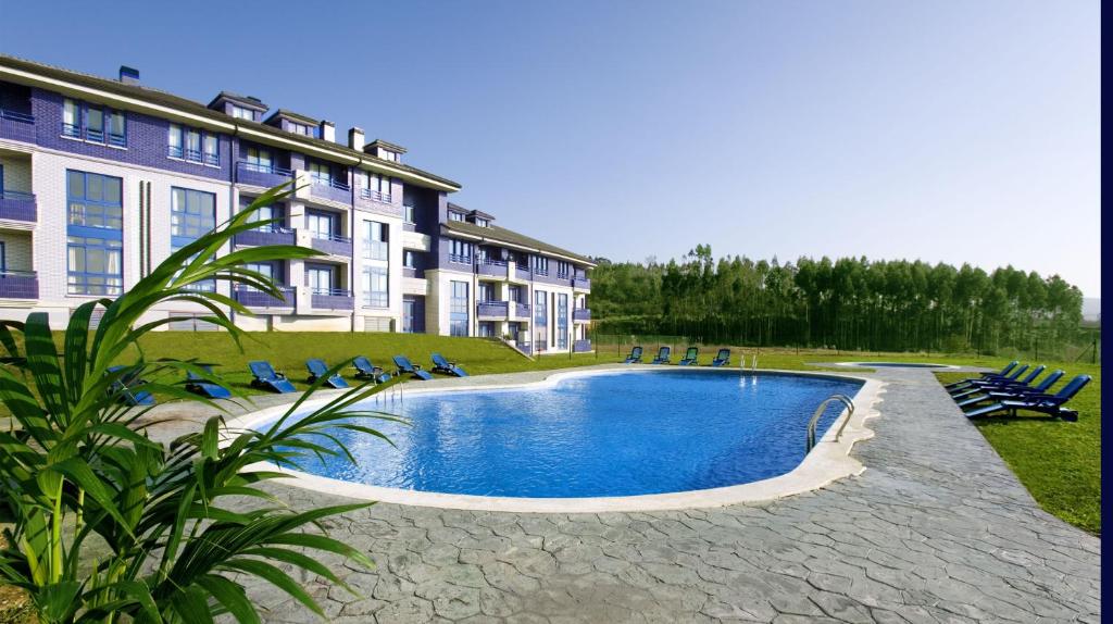 una piscina frente a un gran edificio en Apartamentos Dunas de Liencres, en Boó de Piélagos