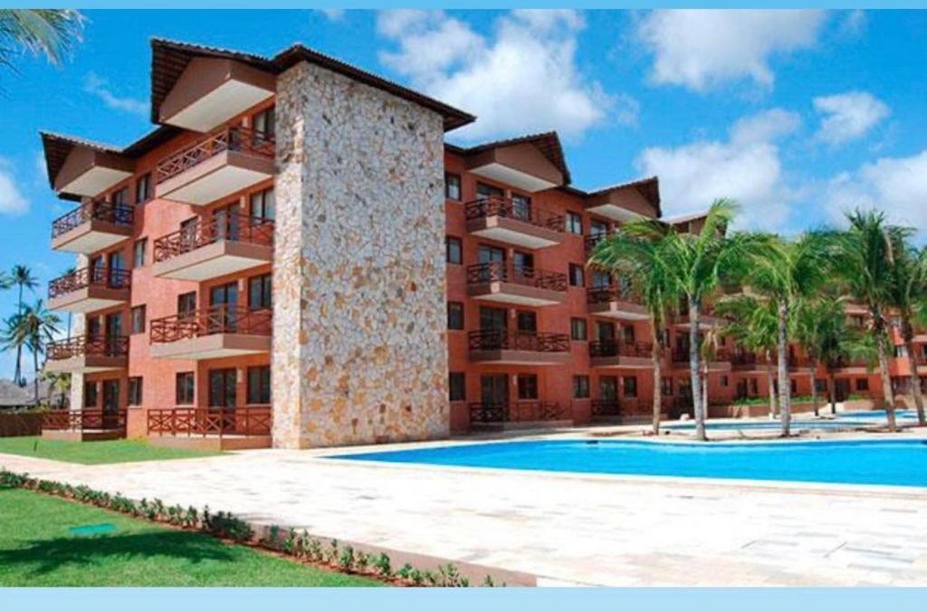 um grande edifício de apartamentos com piscina e palmeiras em Beach Kariri Residence Privado em Cumbuco