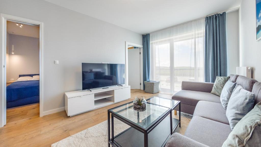 a living room with a couch and a tv at Apartamenty Sun & Snow BLUE II in Sarbinowo