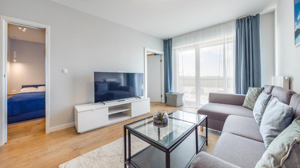 salon z kanapą i telewizorem w obiekcie Apartamenty Sun & Snow BLUE II w Sarbinowie