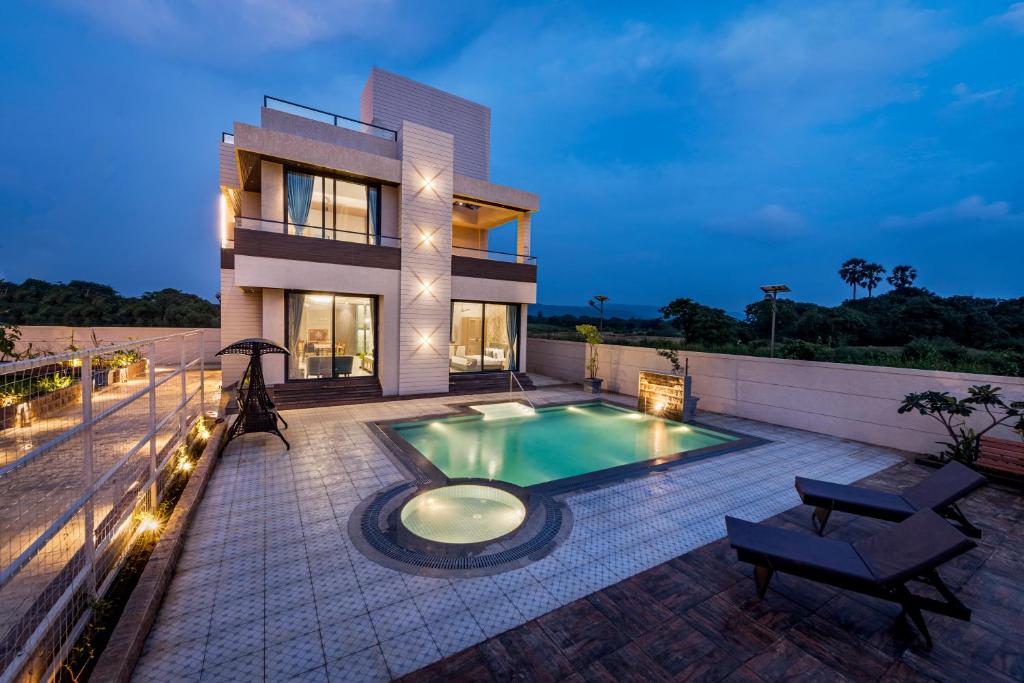 a villa with a swimming pool in front of a house at SaffronStays Nishta - 4BR pet-friendly villa with pool, turf, gazebo & terrace BBQ views in Alibaug in Alibaug