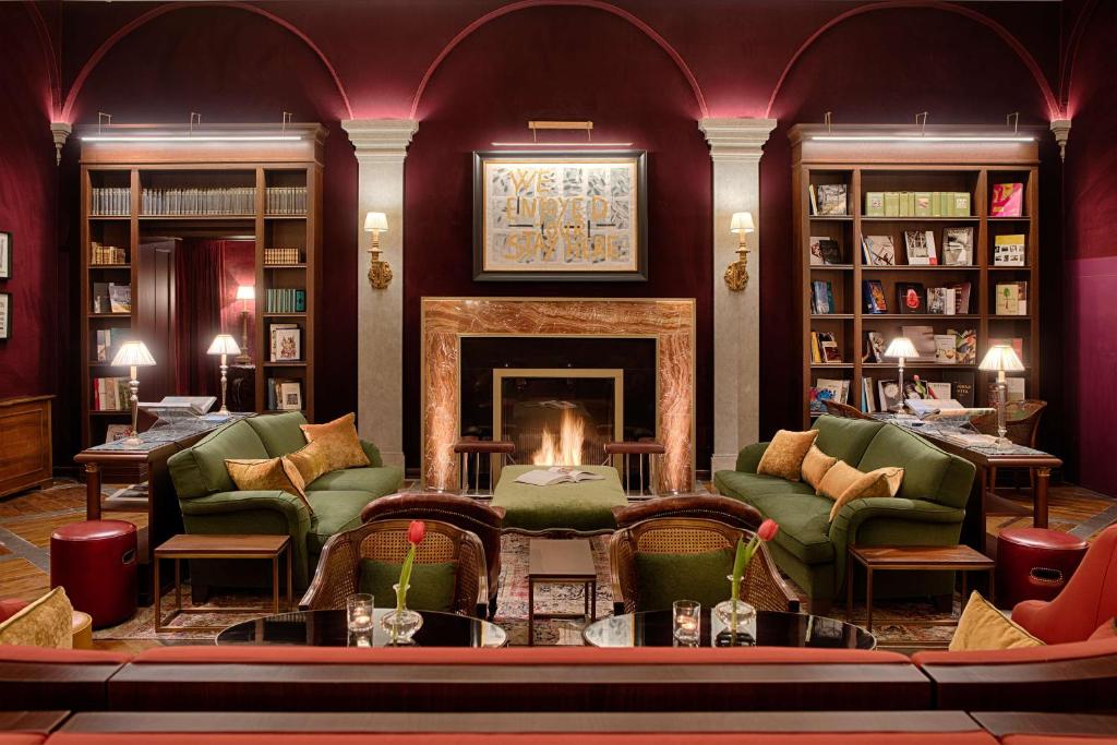 a living room with a fireplace and green chairs at NH Collection Palazzo Gaddi in Florence