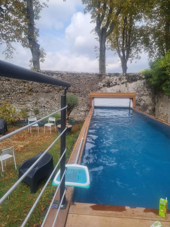 - une piscine dans une cour avec des chaises et un mur dans l'établissement Gîte de la Mignonerie du Château de Jallanges pour 19 personnes avec 4 ou 7 chambres, à Vernou-sur-Brenne