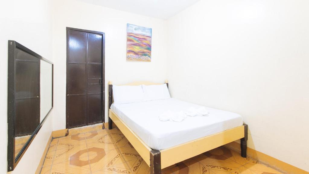 Una cama blanca en una habitación con un cuadro en la pared en Golden Pegasus Hotel La Union by RedDoorz, en San Juan