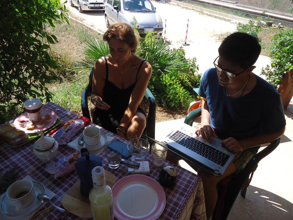 un hombre y una mujer sentados en una mesa con un portátil en Le Sete, en Bari