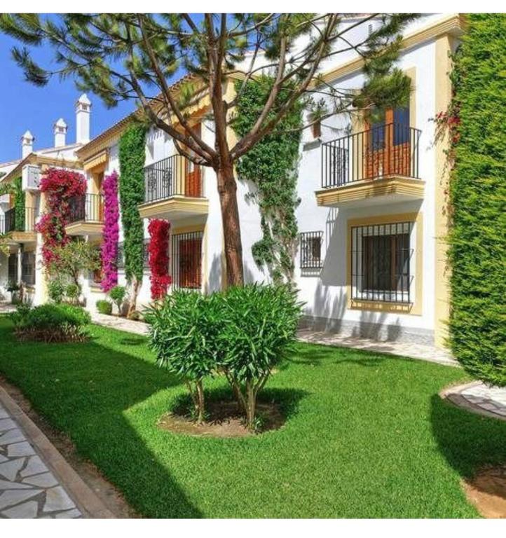 duży biały dom z drzewem w ogrodzie w obiekcie Apartamento jardines tropicales dos piscinas vera playa las marinas urbanización vera coast w mieście Vera