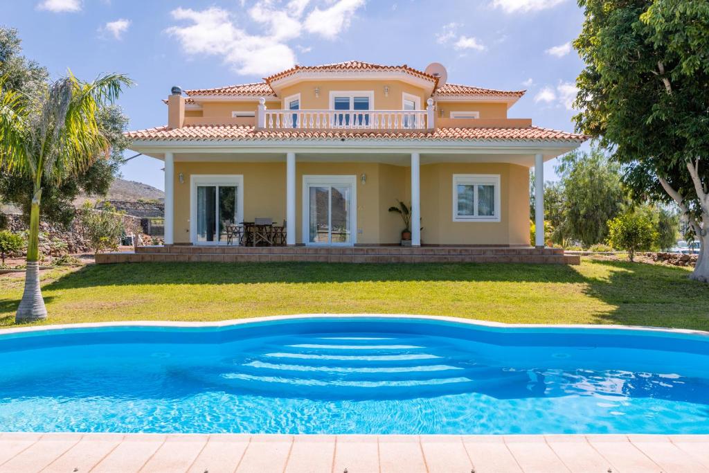 a villa with a swimming pool in front of a house at Modern Villa with heated pool and mountain views in Arona