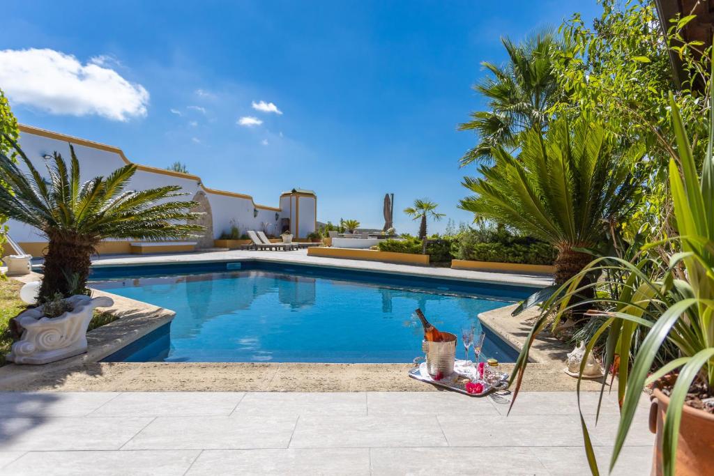 una piscina en un patio trasero con palmeras en QUINTA DO MONTE DAS ABELHAS - La Vénus de Lisbonne, en Calhandriz