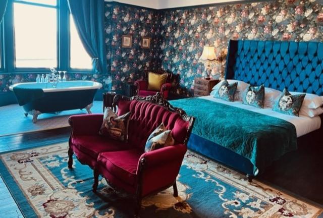 ein Schlafzimmer mit einem Bett, einem Stuhl und einer Badewanne in der Unterkunft The Gin Lounge Rooms in Ilkley