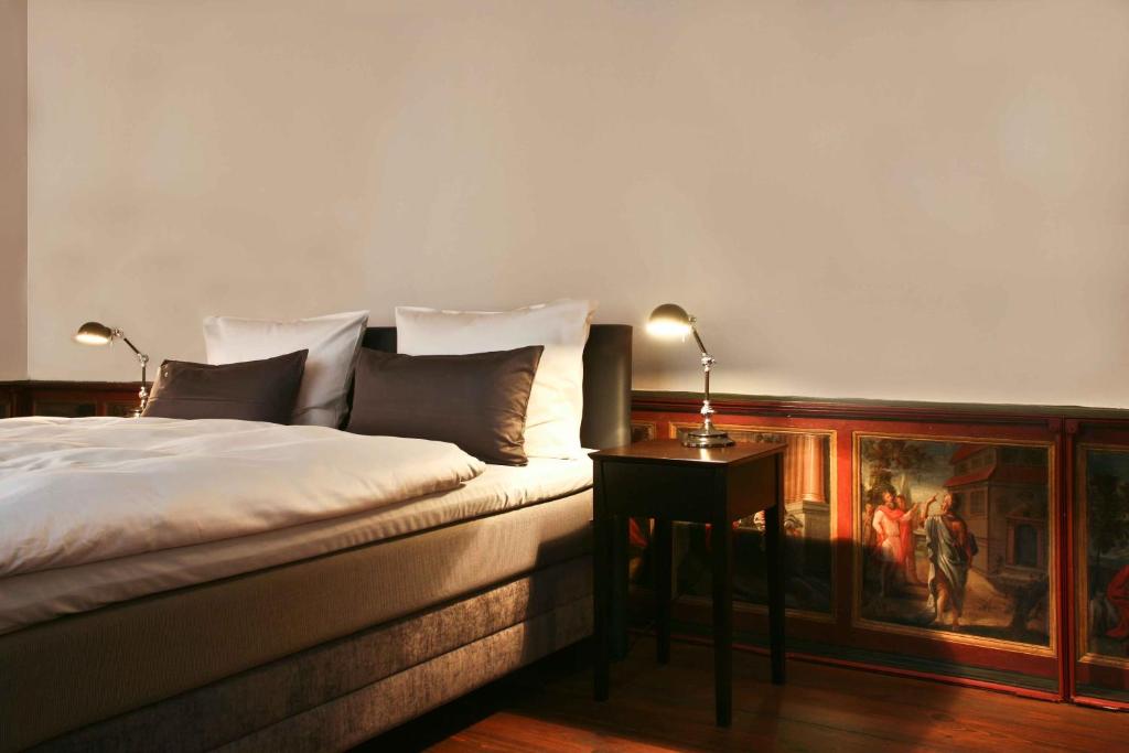 a bedroom with a bed and a table with a painting at Hotel Anno 1216 in Lübeck